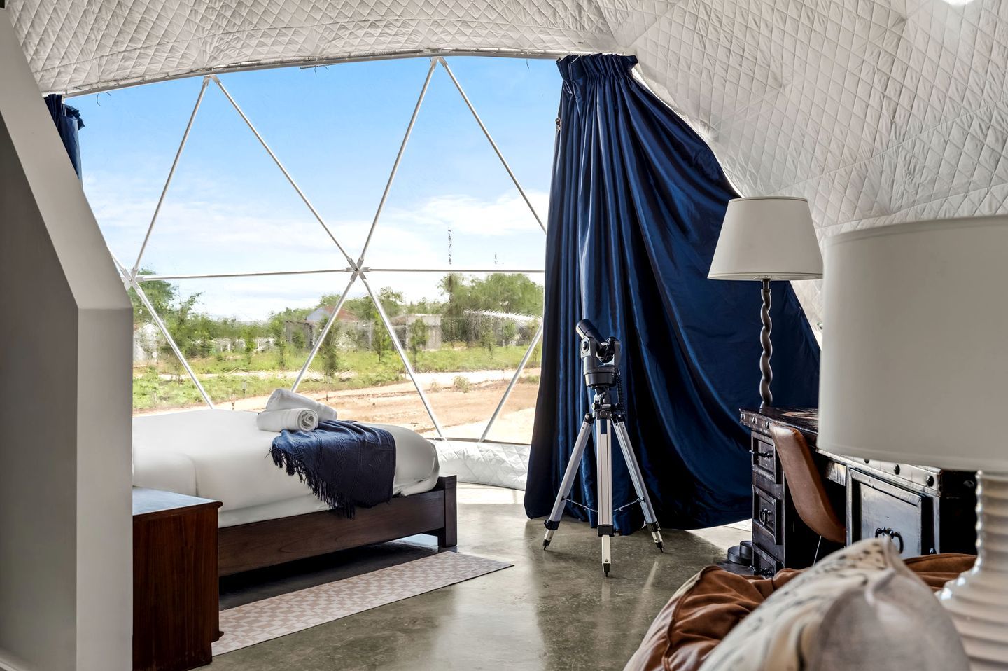 Ein Zeltraum mit einem Bett, einem Teleskop und einer Lampe.