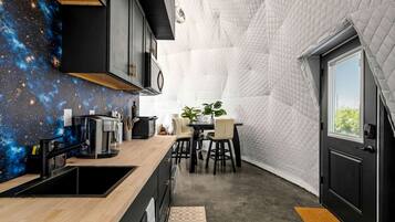 A compact kitchen with a galaxy-themed backsplash, a dining area with a table and chairs, and a door with a window.