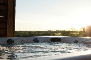 Ein Whirlpool mit Blick auf eine Landschaft bei Sonnenuntergang.