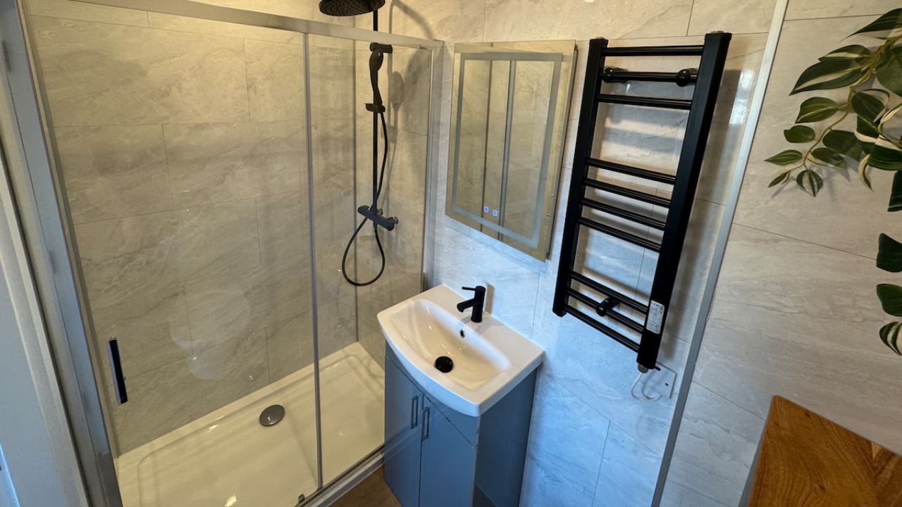 A bathroom with a glass-enclosed shower, a white sink, and a towel rack.