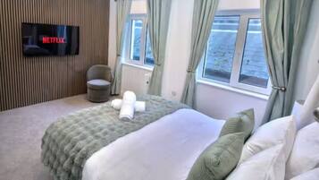 Una habitación de hotel con una cama, una silla, un televisor de pantalla plana y un ventanal.