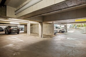 An underground parking garage with concrete pillars, marked parking spaces, and a few cars parked. - Modern apartment in the heart of Wiesbaden. Ideal for temporary housing. (Wiesbaden)
