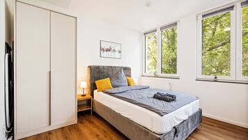 A bedroom with a bed, bedside table, lamp, and a cityscape picture on the wall.