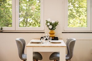 A dining table with chairs, a vase with flowers, and glasses. - Modern apartment in the heart of Wiesbaden. Ideal for temporary housing. (Wiesbaden)