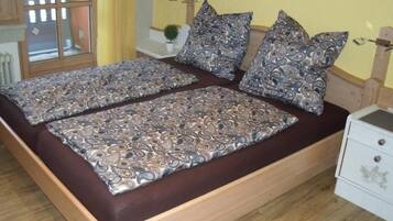 Una cama doble con ropa de cama y almohadas estampadas, un cabecero de madera, una mesita de noche con una lámpara y una ventana con vistas.