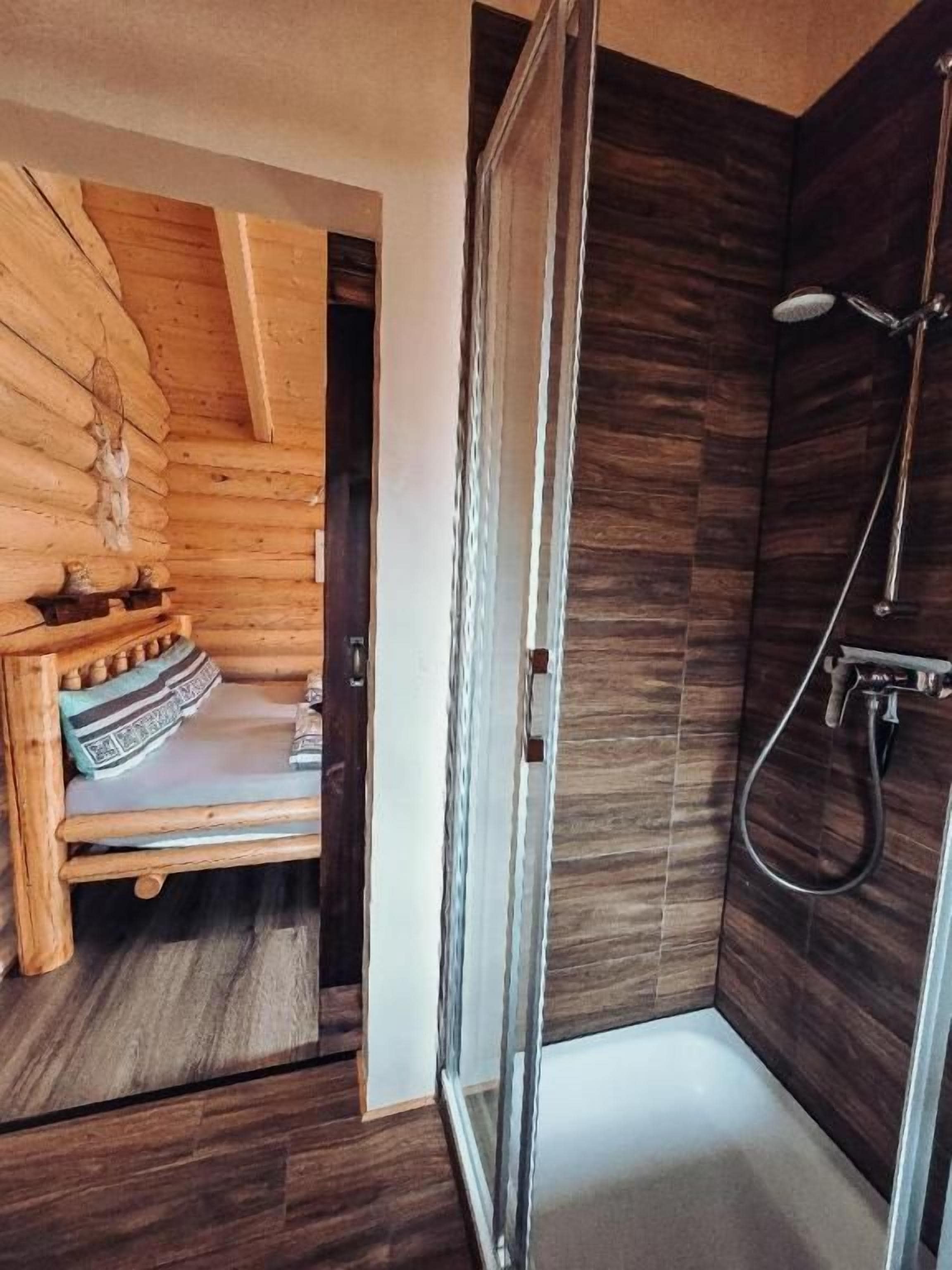 A wooden cabin interior with a shower area and a bench.