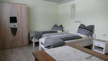 A bedroom with two beds, a wardrobe, a bedside table, and a dreamcatcher on the wall.