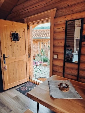 A wooden interior with a door leading outside, a table with a placemat, and a small decorative item on the table.