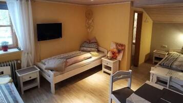 A room with a bed, a table, chairs, a TV, and a window.