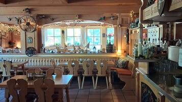 Un restaurant amb mobles de fusta, una zona de bar i vistes a través de grans finestres.
