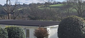 A building with a flat roof, surrounded by trees and a green field in the background. - Apartment Room 1 Sleeps 2 With Wifi (Saltash)