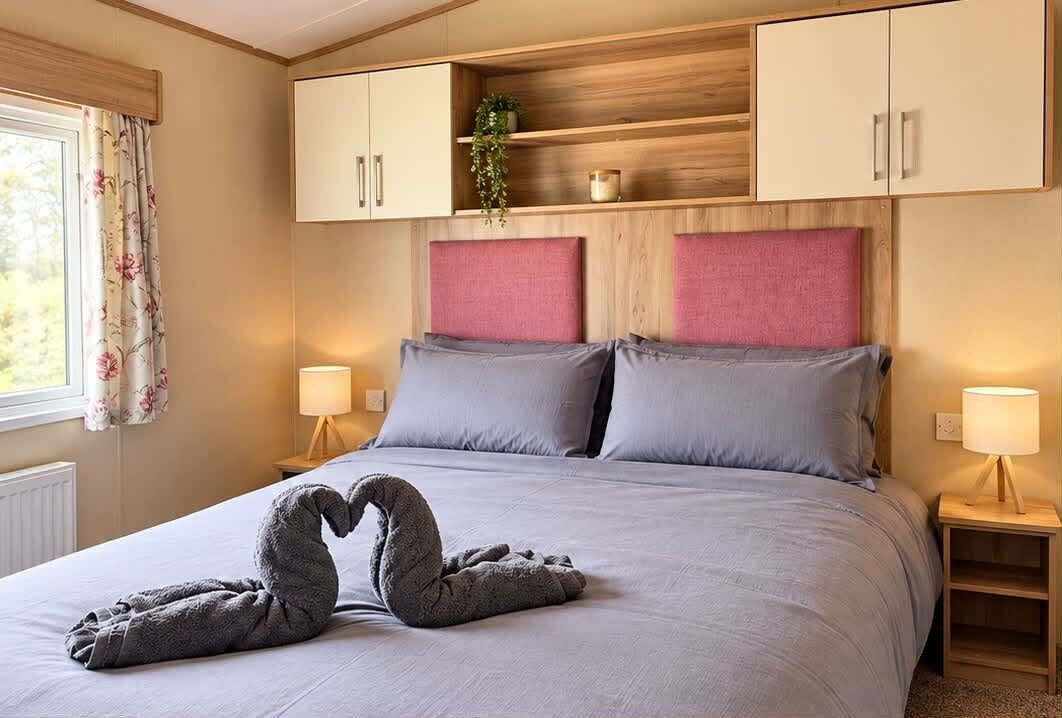 Une chambre à coucher comprenant un lit, deux tables de chevet, une fenêtre avec des rideaux et des armoires encastrées en bois.