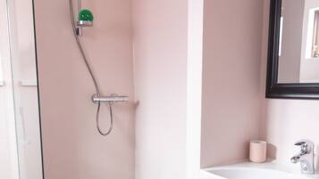 A modern bathroom with a glass shower enclosure, a white vanity, and a black tiled floor.
