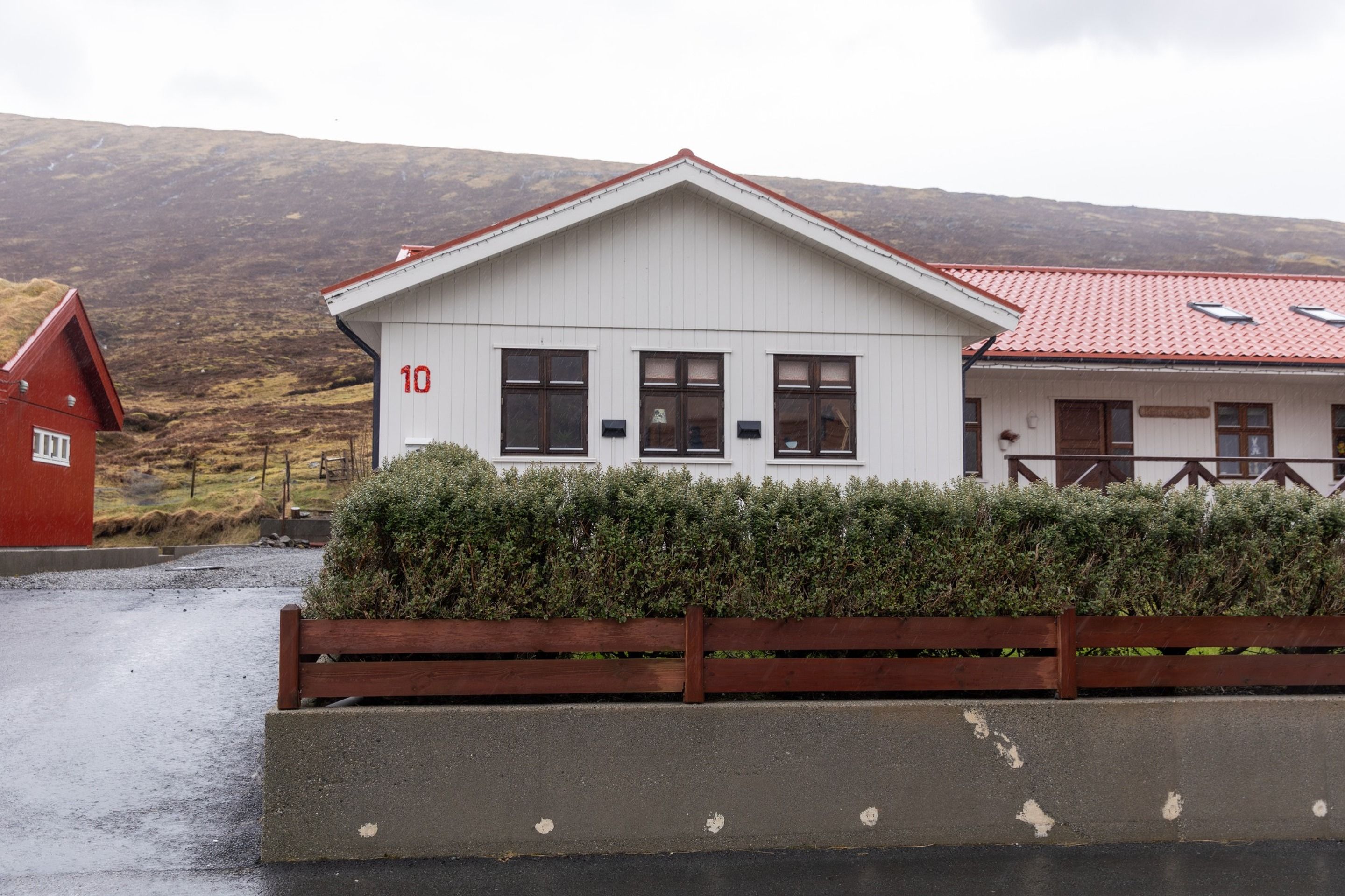 A white building with the number 10, a red roof, and a wooden fence in front.