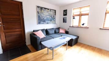 Een moderne woonkamer met een grijze bank, een bijzettafeltje en een groot abstract schilderij aan de muur.