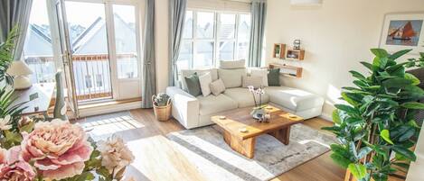 Una sala de estar con sofá, mesa de centro y una planta.