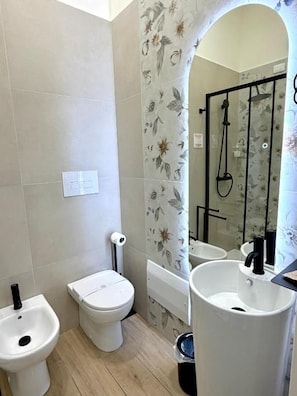 A bathroom with a toilet, bidet, sink, and shower. - Xenia Suites Duomo (Reggio Calabria)