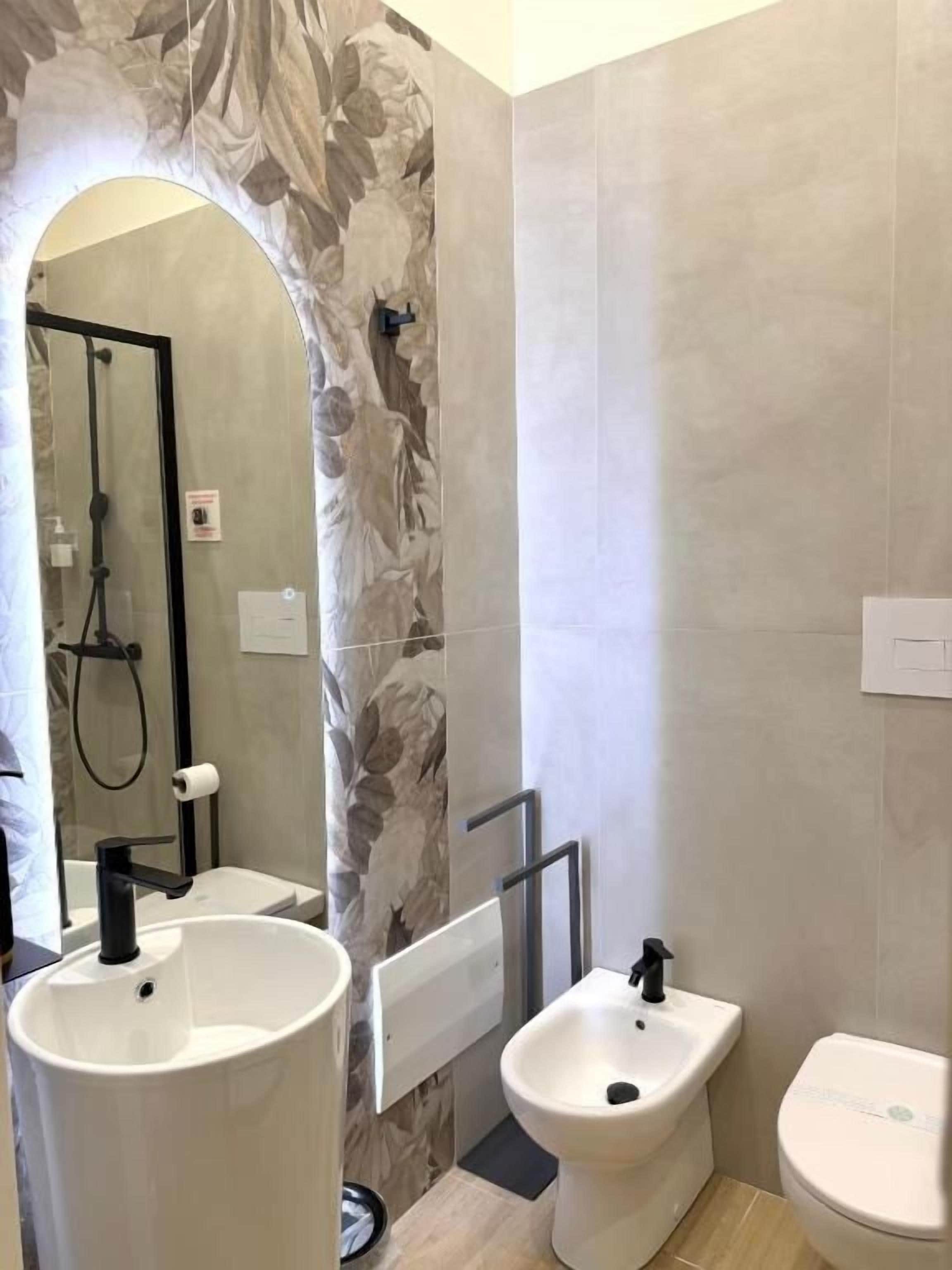 Un baño con un espejo grande, un lavabo, un bidé y un inodoro.