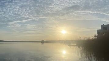 Ruhige Wasseroberfläche spiegelt den Himmel und ein Gebäude mit flachem Dach.