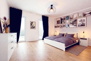 A bedroom with a bed, bedside tables, a dresser, and a large window.