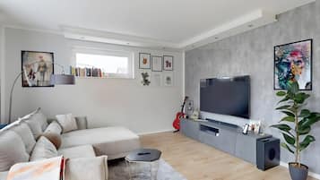 Un saló modern amb un sofà, una televisió i obres d'art a les parets.