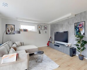 A modern living room with a sofa, a TV, and artwork on the walls.