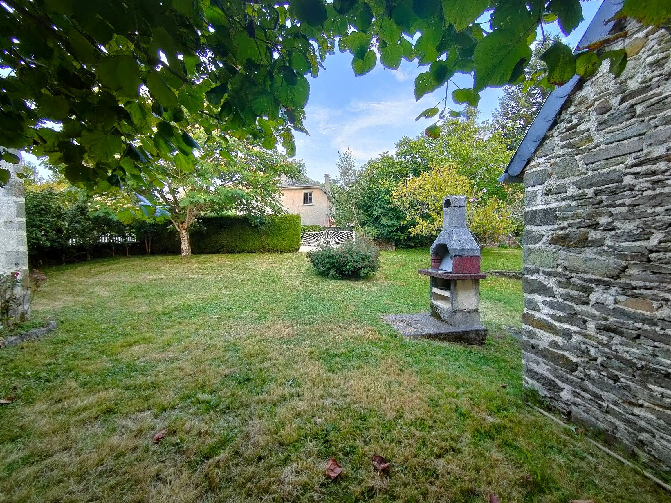 A stone building with a chimney, a grassy yard, and a metal sculpture.