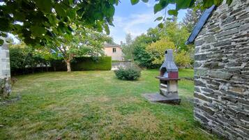 A stone building with a chimney, a grassy yard, and a metal sculpture.