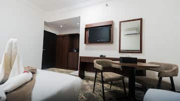 A hotel room with a bed, a desk with two chairs, a television, and a mirror.