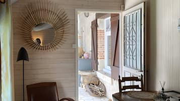 A room with a wooden floor, a dining table with chairs, a lamp, and a decorative mirror.