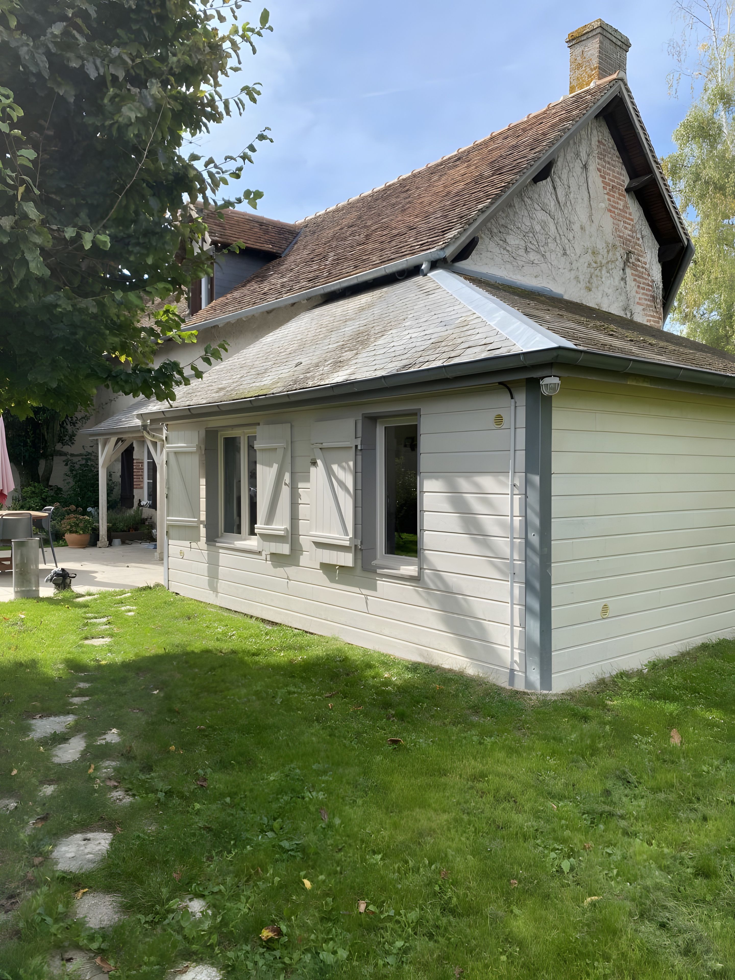 Une maison de plain-pied avec un toit en pente, une véranda et une pelouse bien entretenue.