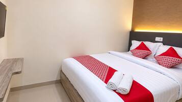 Habitación de hotel con una cama, un televisor de pantalla plana montado en la pared y una mesita de noche de madera.