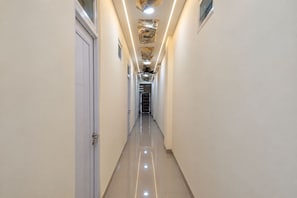 A long, narrow hallway with a shiny floor, white walls, and a ceiling with a decorative pattern.