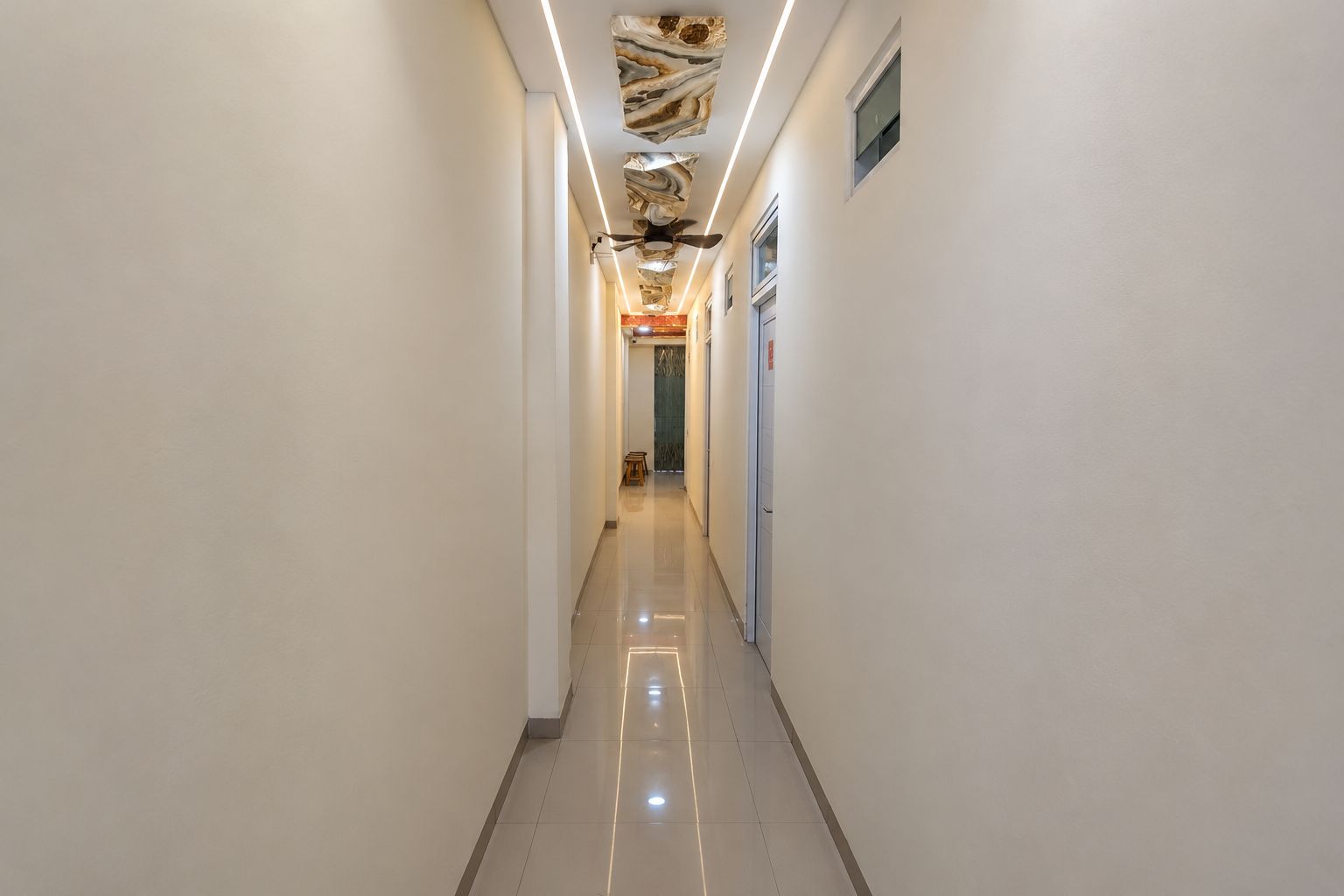 A hallway with a polished floor, white walls, and a ceiling with a unique design.