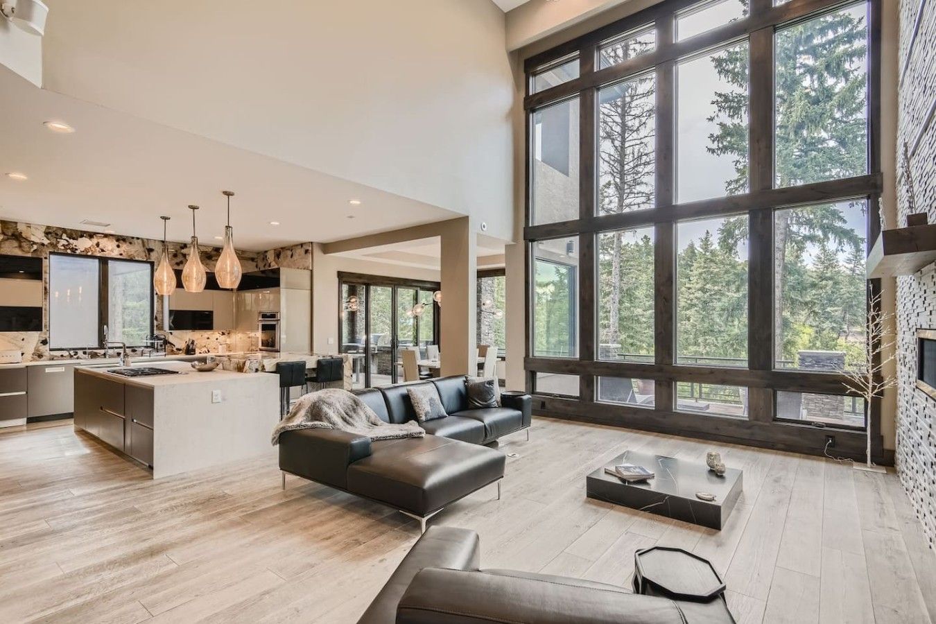A spacious living area with a large window, a modern kitchen, and a seating area.