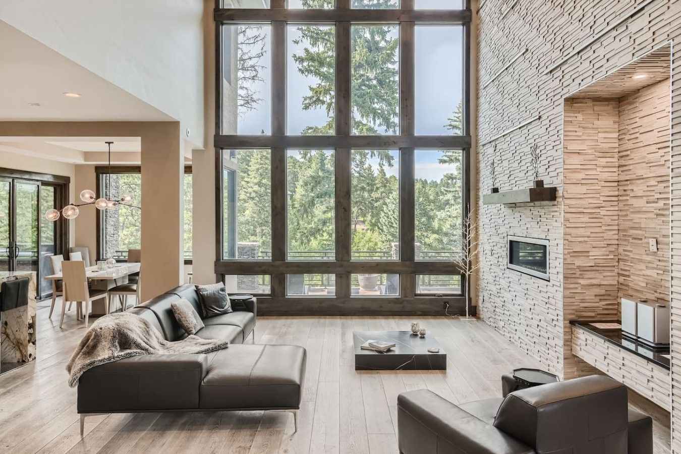 A spacious living area with a large window, a fireplace, and a modern kitchen.