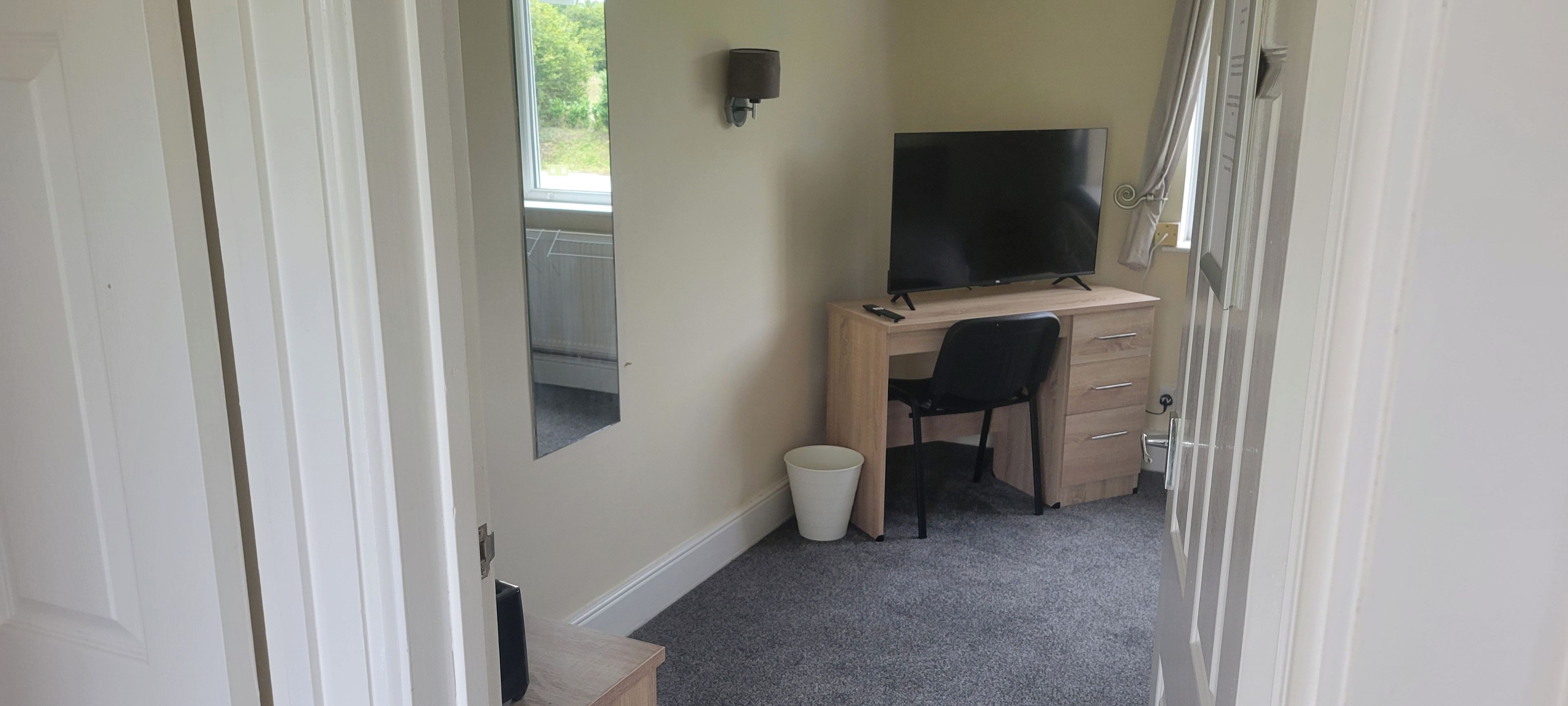 Een kamer met een bureau, stoel en een televisie.