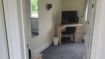 Een kamer met een bureau, stoel en een televisie.