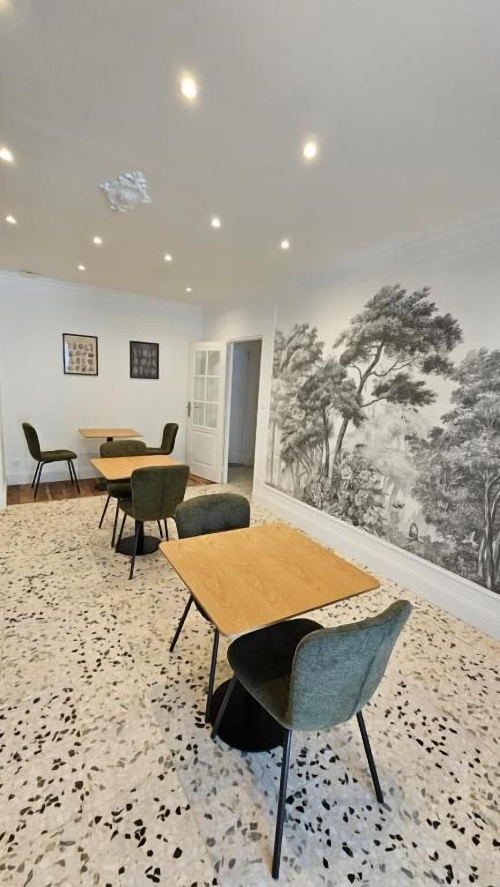 Un comedor con una mesa, sillas, un mural en la pared y un piso moteado.