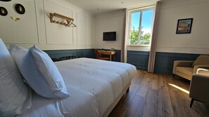 Hotellihuone, jossa on suuri sänky, työpöytä, tuoli ja televisio.