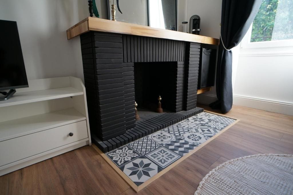 Un salon moderne avec une cheminée en briques noires, un meuble TV blanc et un tapis à motifs.