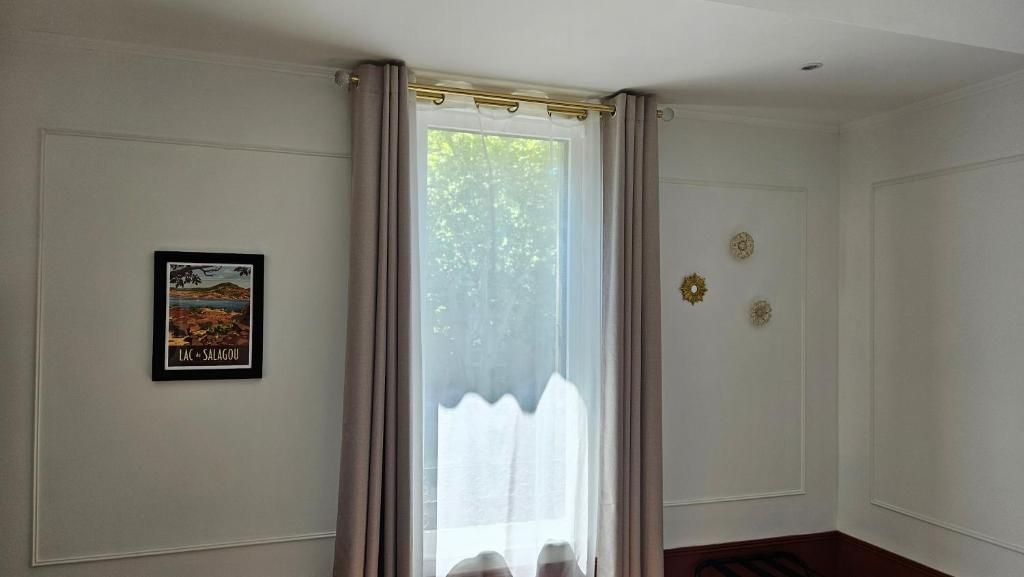 A room with a door, a framed picture on the wall, and a window with curtains.