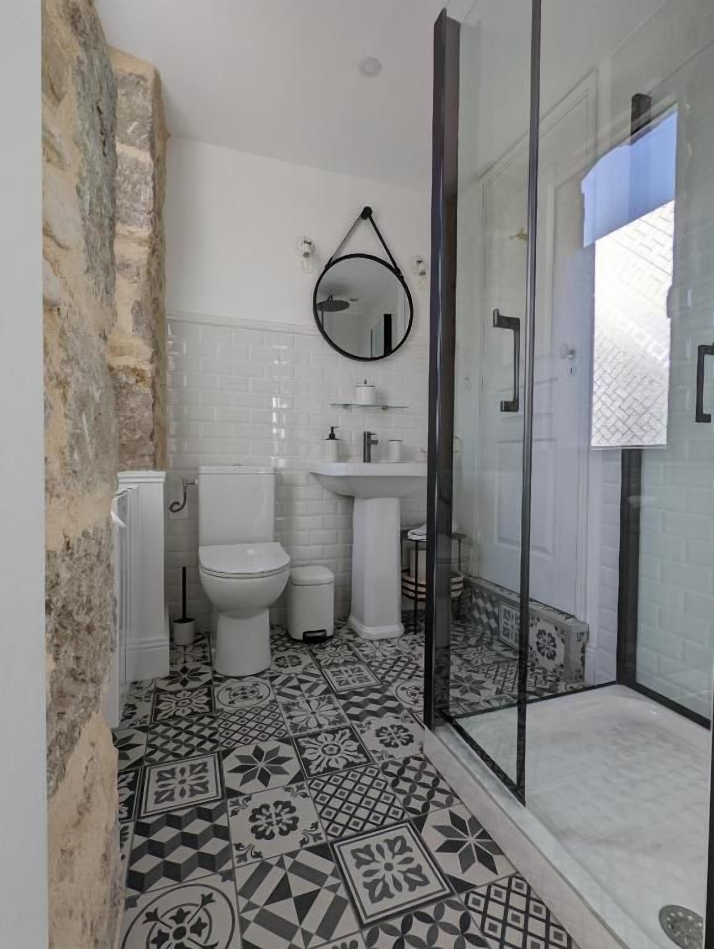 Une salle de bain équipée d’une douche, de toilettes, d’un lavabo et d’un miroir.