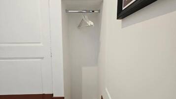 Un pasillo con una puerta blanca, un perchero y un cuadro en la pared.