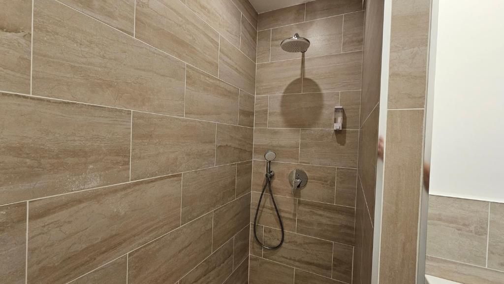 Zona de ducha con ducha de mano y grifo empotrado.
