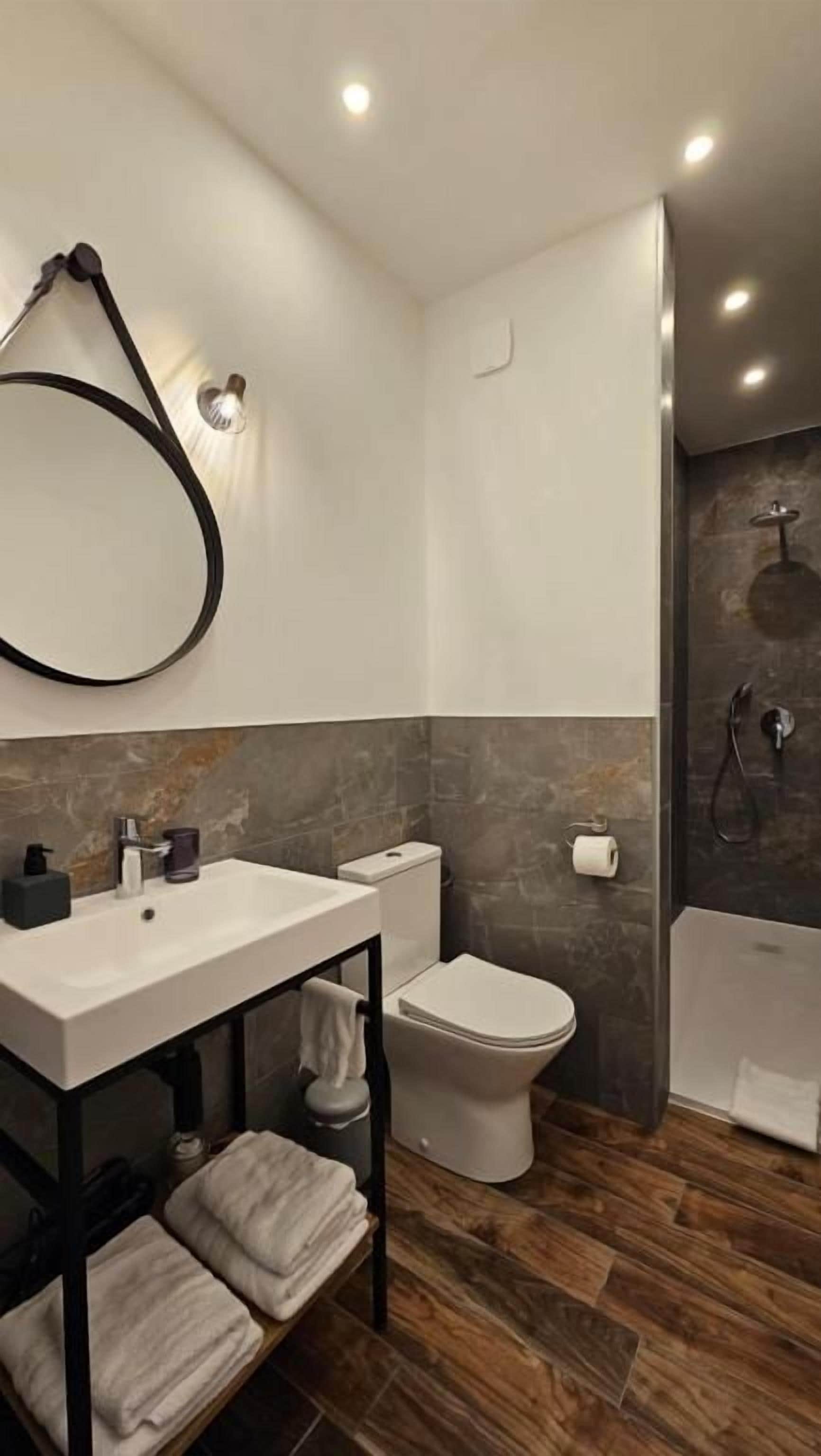 Une salle de bain moderne avec un lavabo, des toilettes et une zone de douche, le tout de couleur blanche.
