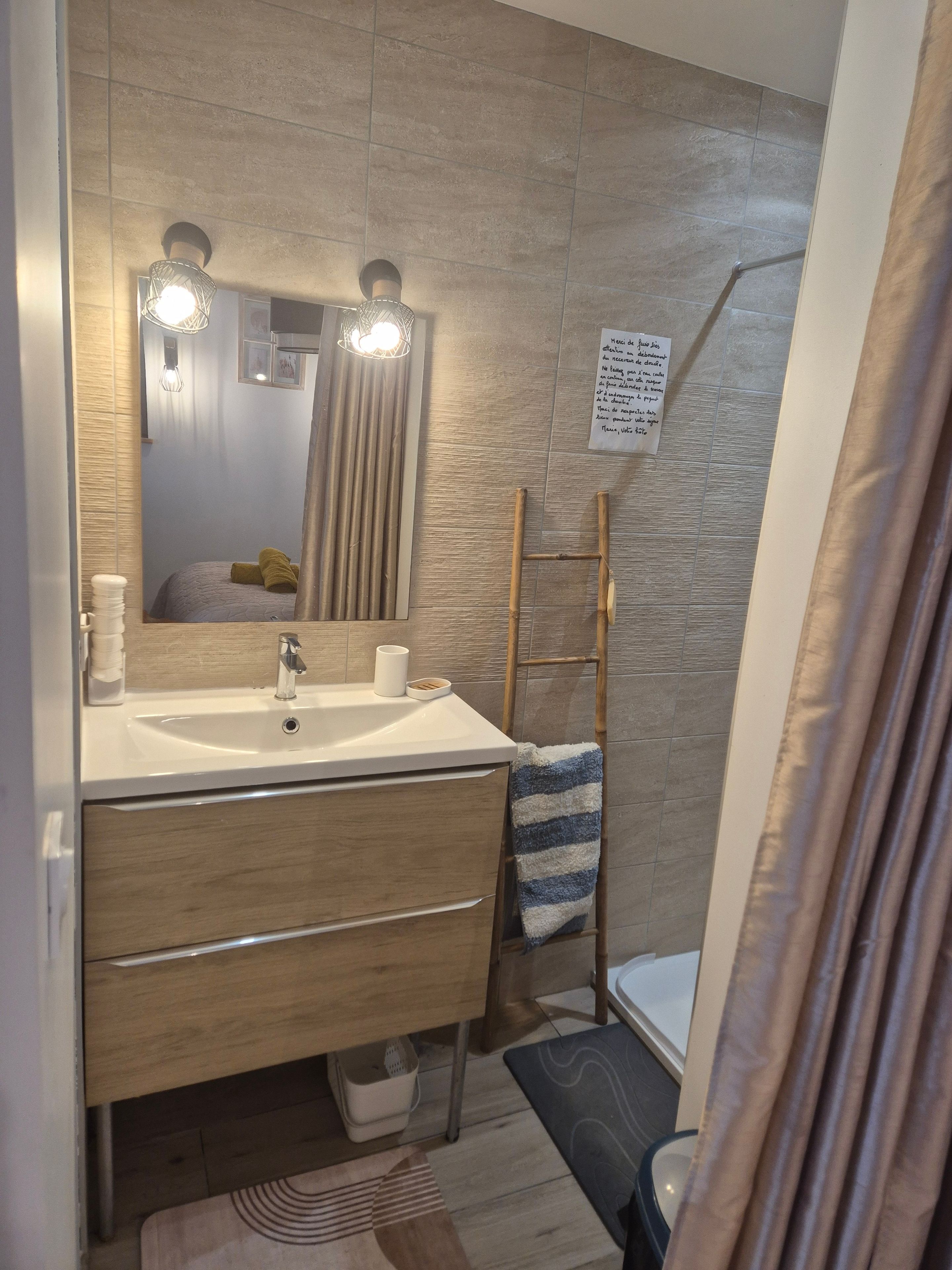 Un baño moderno con lavamanos, espejo, toallero y un cartel en la pared.