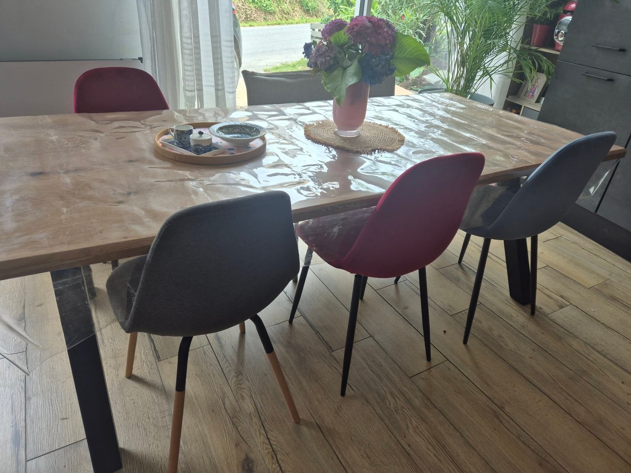 Une table à manger avec des chaises, un plateau avec des tasses et une théière, et une plante en pot.