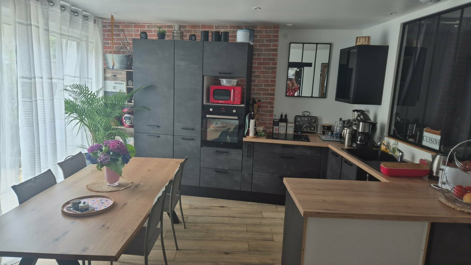 Een compacte keuken met een eethoek, met een houten tafel, stoelen, een koelkast, een magnetron en een koffiezetapparaat.