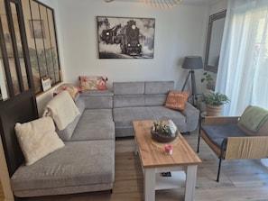Ein modernes Wohnzimmer mit einem grauen Ecksofa, einem Holztisch und einem schwarzen und weißen Gemälde eines Zuges an der Wand.